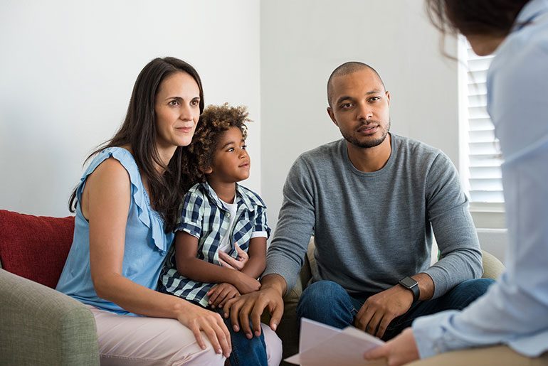 family of three sitting down with someone talking